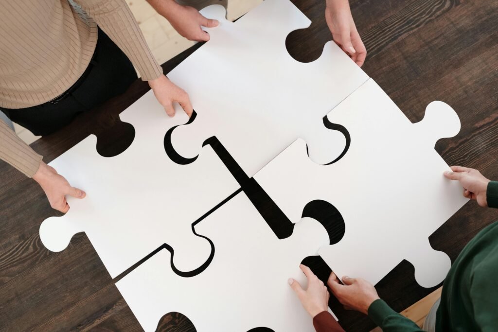 pexels-photo-6147381-6147381 Group collaborating on assembling large puzzle pieces symbolizing teamwork and unity.